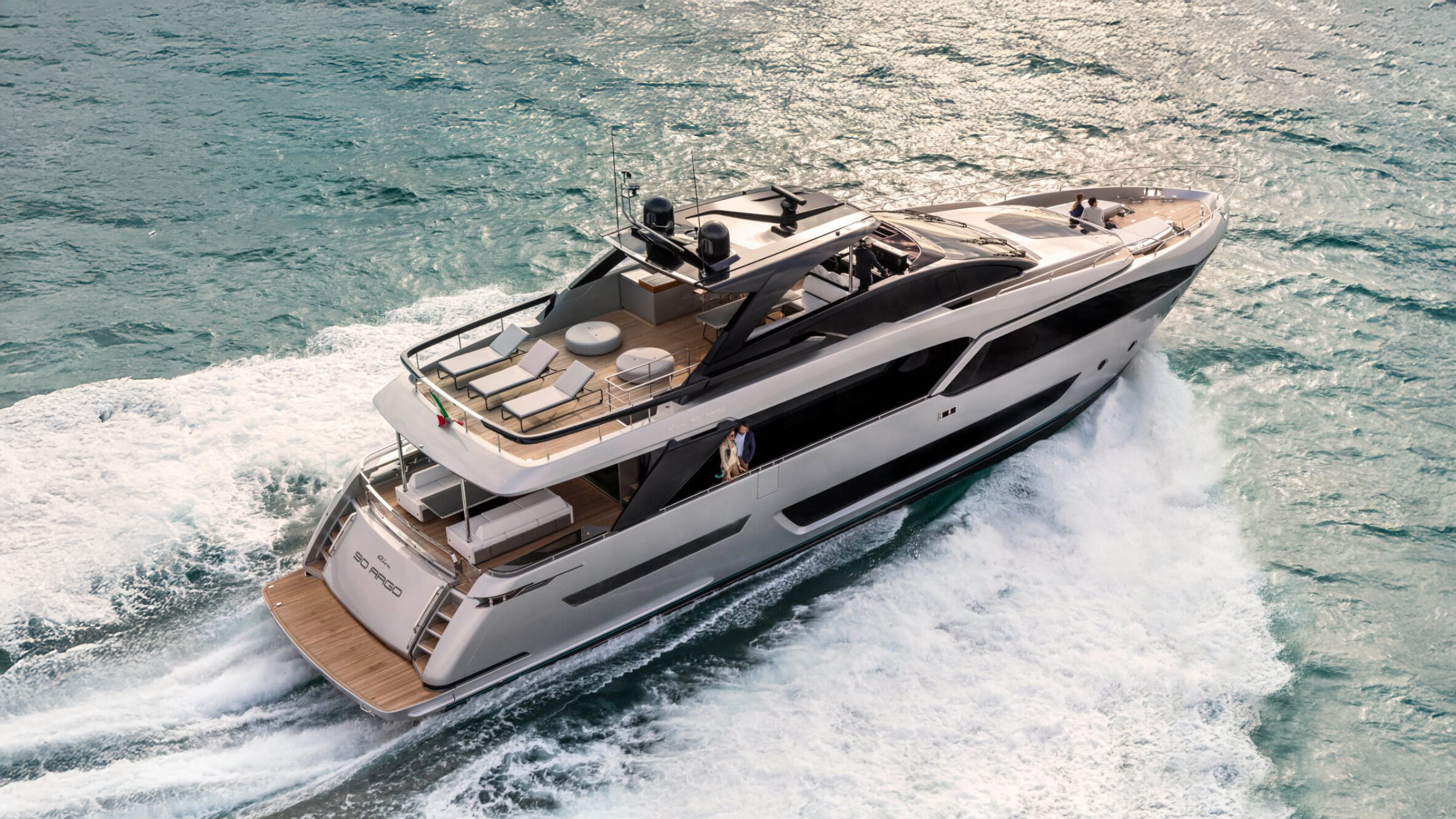 Yacht crusing through a light sea with a couple watching the view