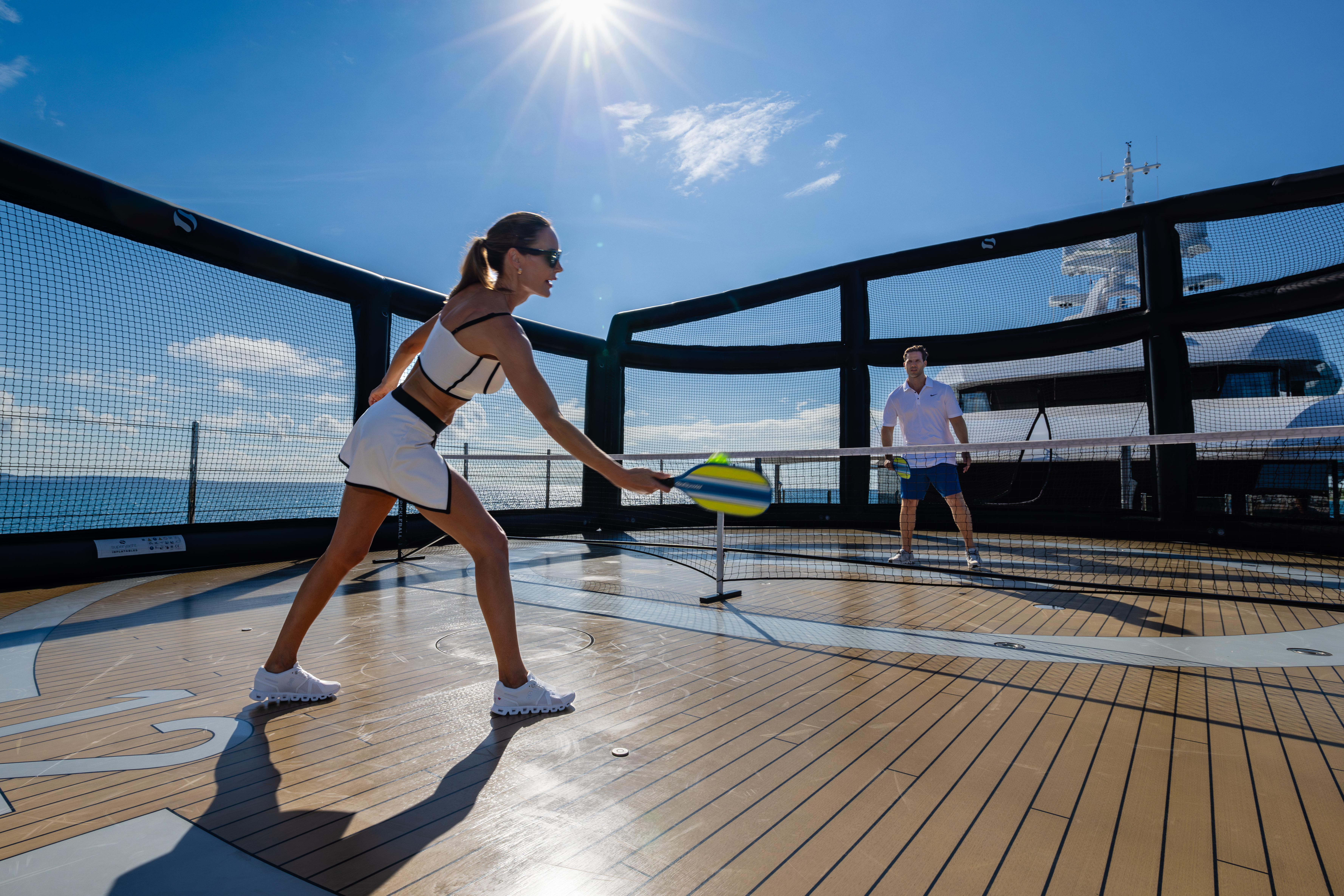 A Man and Woman playing Pickleball on the Deck of a Yacht