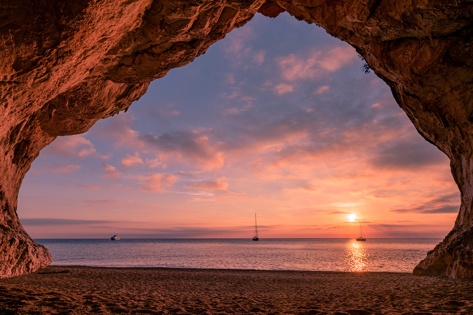 Cala Mitjana is a tranquil cove with turquoise waters, golden sand, and lush pine forests.