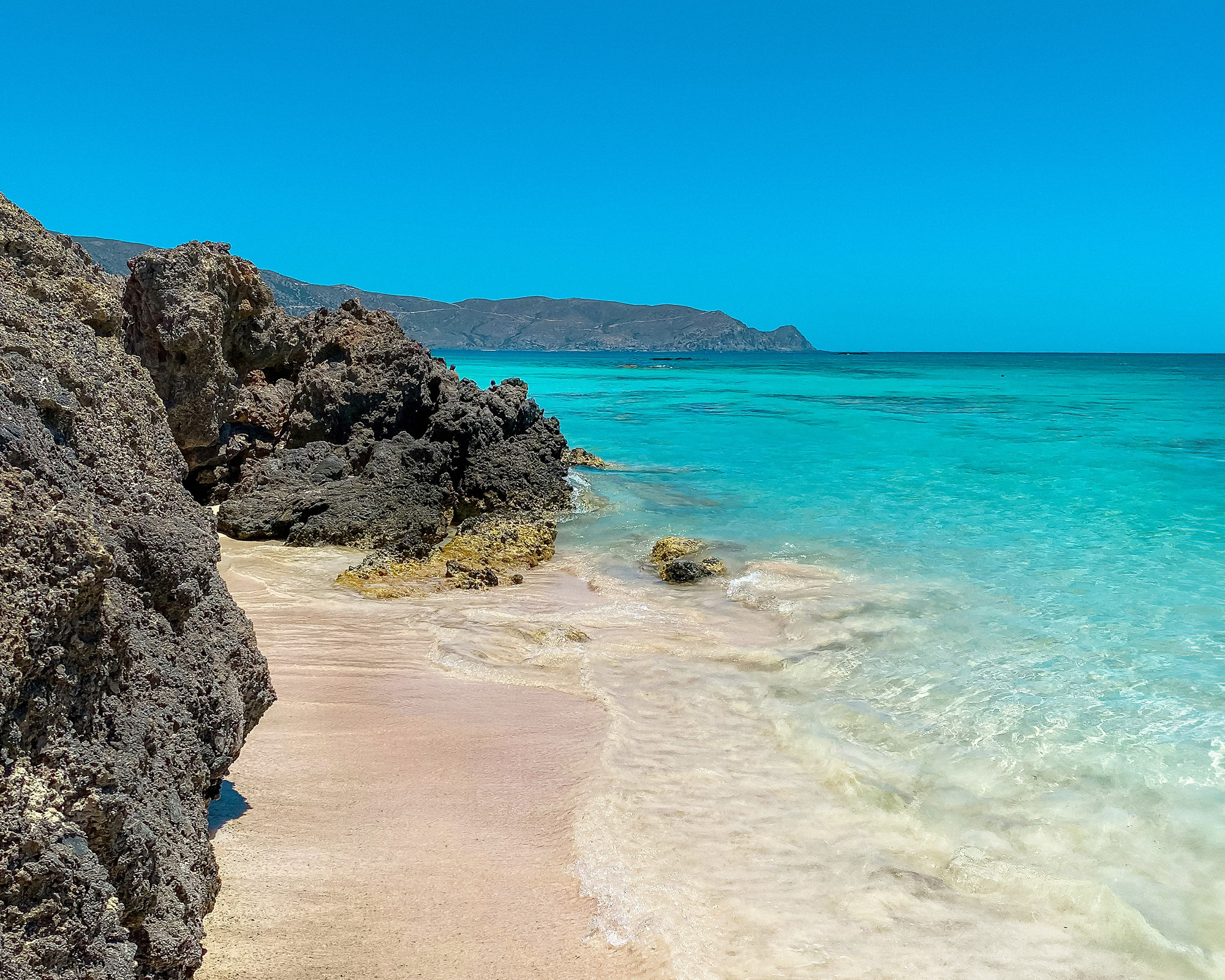 Elafonissi Beach is renowned for its pink sand, shallow turquoise waters, and natural lagoon