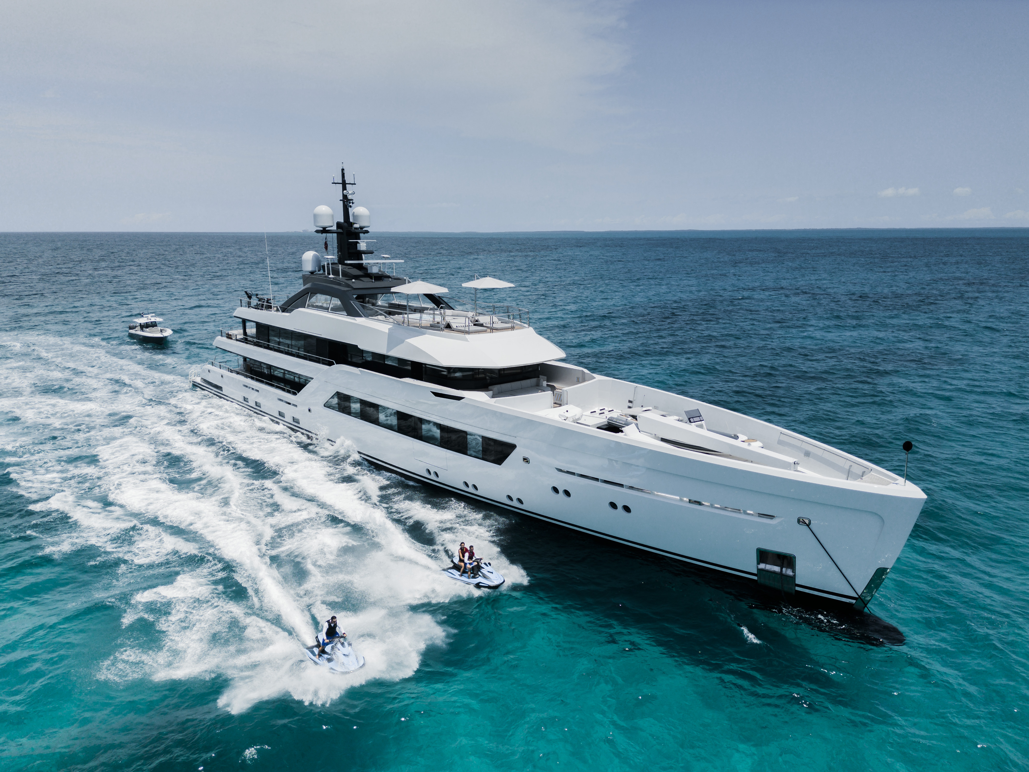 White Yacht on the waters with People on Jetskis Next to It